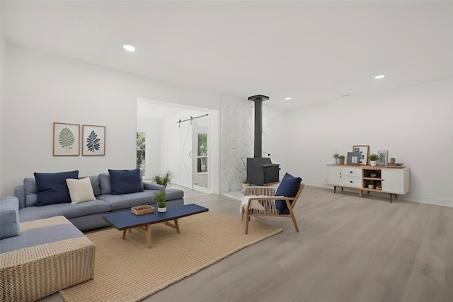 living room featuring baseboards, light wood finished floors, a wood stove, and recessed lighting