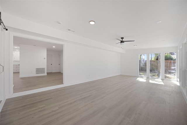 unfurnished living room with light wood-style flooring, a barn door, and visible vents