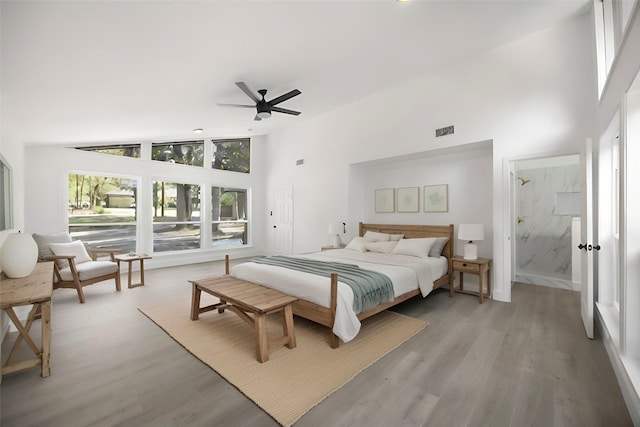 bedroom with visible vents, ensuite bathroom, light wood-style floors, ceiling fan, and high vaulted ceiling