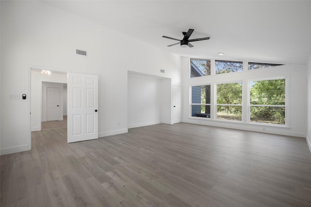 unfurnished living room featuring ceiling fan, high vaulted ceiling, wood finished floors, visible vents, and baseboards