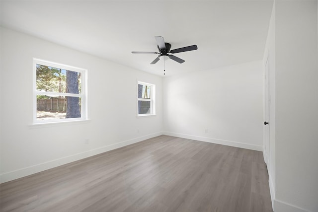 spare room featuring ceiling fan, baseboards, and wood finished floors