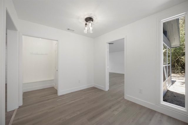 unfurnished room featuring visible vents, baseboards, and wood finished floors