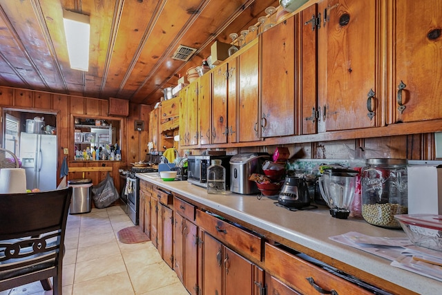 kitchen featuring wooden ceiling, white fridge with ice dispenser, brown cabinets, and light countertops