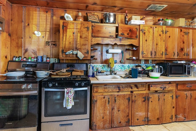 kitchen with brown cabinets, stainless steel appliances, a sink, and light countertops