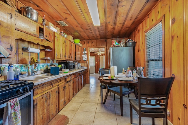 kitchen featuring light tile patterned floors, brown cabinetry, wood ceiling, appliances with stainless steel finishes, and light countertops