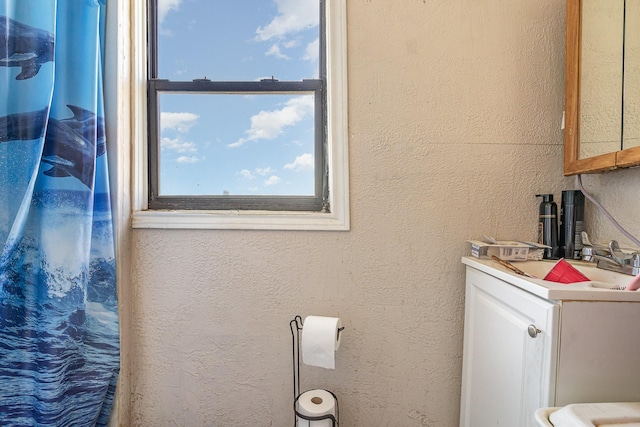 full bath featuring a shower with shower curtain, vanity, and a textured wall