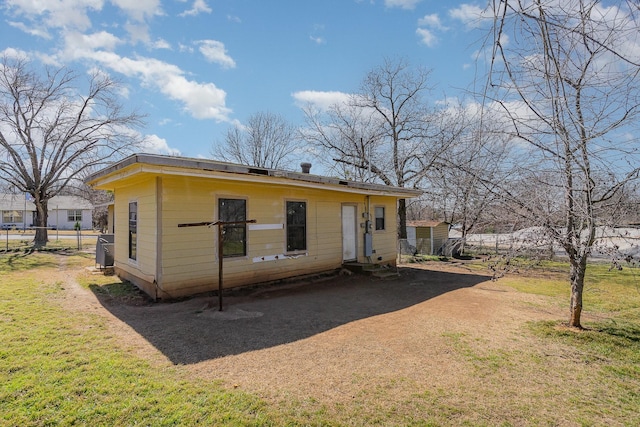 view of front of home with dirt driveway, a front yard, and fence