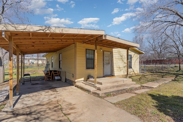 view of front of home with a carport, driveway, and fence