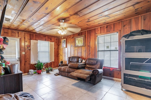 living area with light tile patterned floors, wooden walls, visible vents, wood ceiling, and ceiling fan