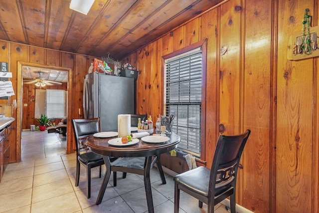 dining area featuring light tile patterned floors, ceiling fan, wooden ceiling, and wooden walls