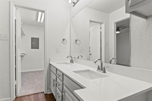 full bathroom featuring double vanity, electric panel, a sink, and wood finished floors