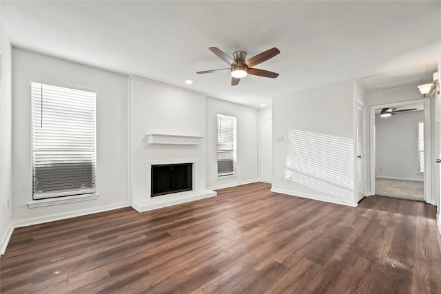 unfurnished living room with a brick fireplace, baseboards, a ceiling fan, and dark wood-type flooring