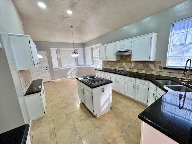 kitchen with under cabinet range hood, gas stovetop, a sink, visible vents, and backsplash