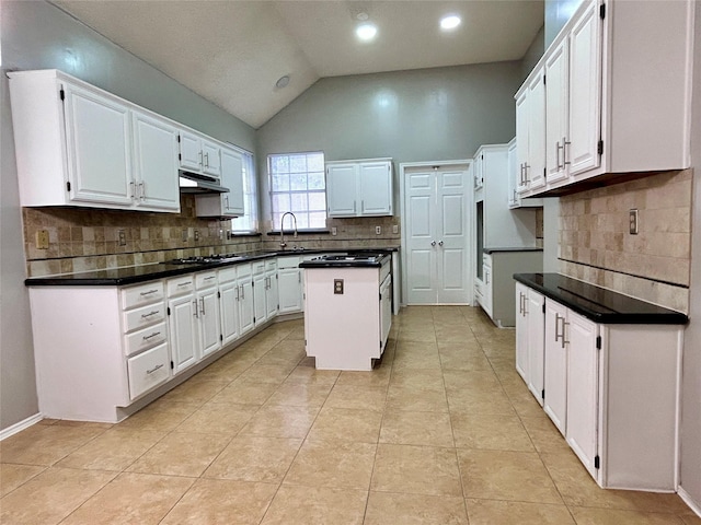 kitchen with lofted ceiling, white cabinetry, a kitchen island, a sink, and under cabinet range hood