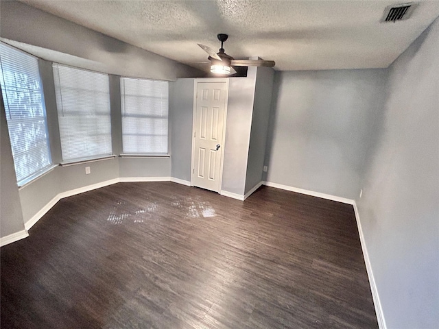 unfurnished bedroom with dark wood-style floors, a textured ceiling, visible vents, and baseboards