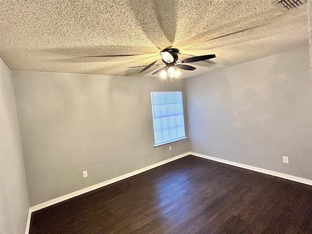 spare room featuring ceiling fan, visible vents, baseboards, and dark wood finished floors