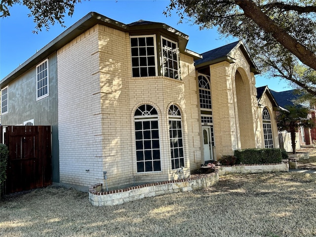 view of side of home with brick siding and fence