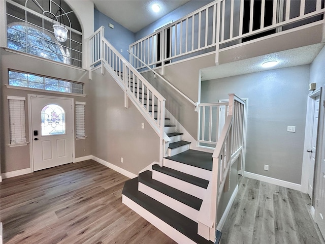 entryway featuring a high ceiling, stairway, wood finished floors, and baseboards