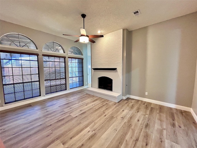 unfurnished living room featuring a large fireplace, wood finished floors, visible vents, and baseboards