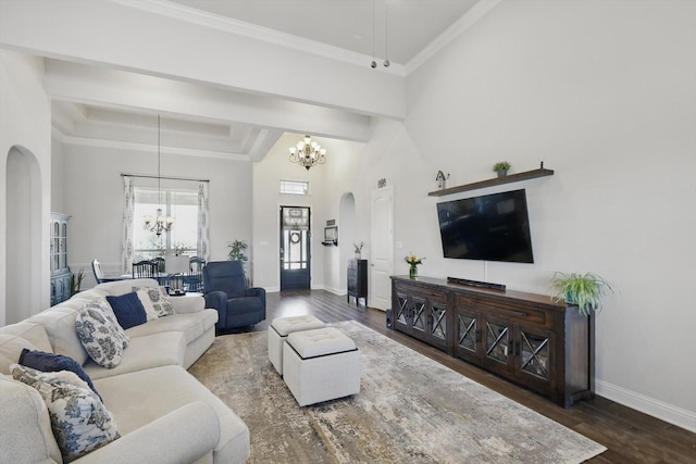 living area with arched walkways, a notable chandelier, a high ceiling, wood finished floors, and baseboards