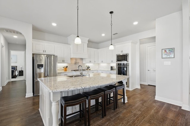 kitchen featuring visible vents, arched walkways, dark wood-style flooring, stainless steel appliances, and a sink