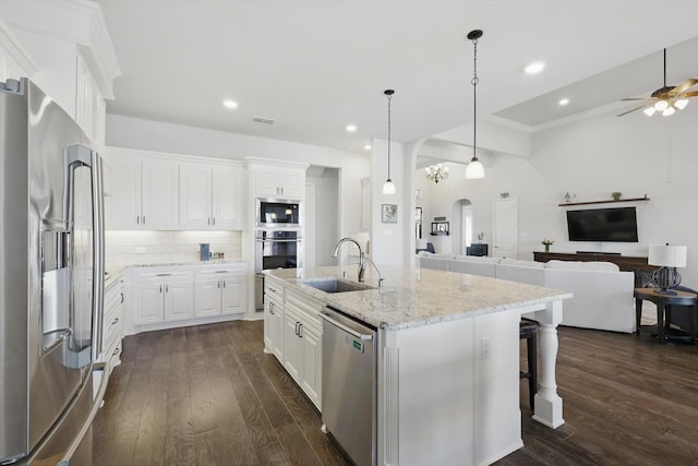 kitchen with arched walkways, dark wood-style flooring, stainless steel appliances, open floor plan, and a sink