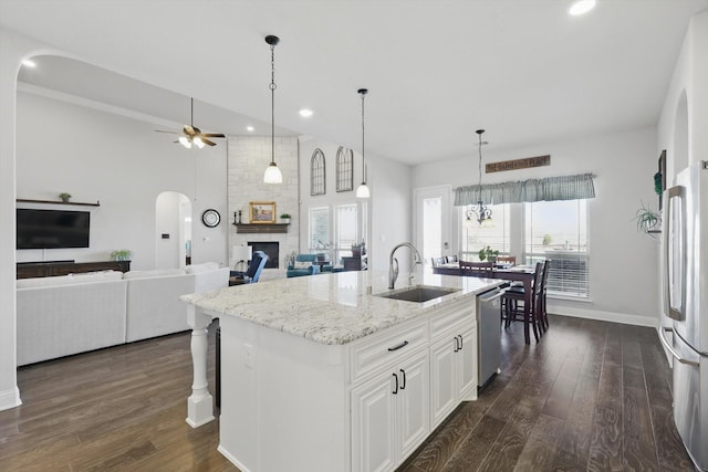 kitchen with stainless steel appliances, dark wood-type flooring, a fireplace, and a sink