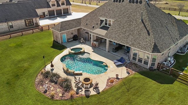 view of pool featuring a pool with connected hot tub, a lawn, a patio area, a fenced backyard, and a fire pit