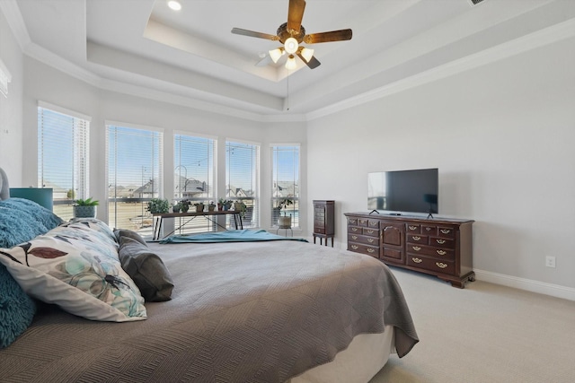 bedroom featuring light carpet, baseboards, a tray ceiling, and ceiling fan