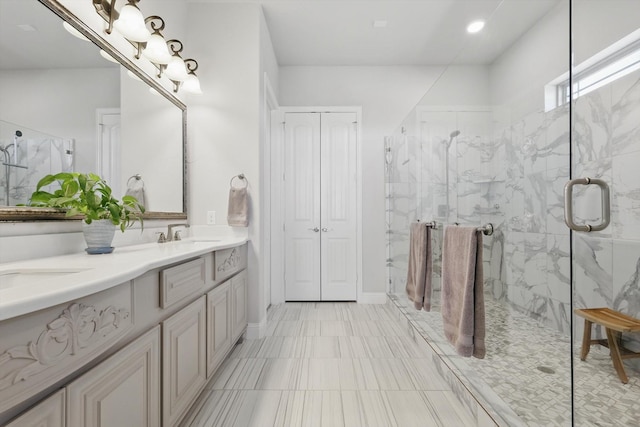 bathroom with a sink, double vanity, and a marble finish shower