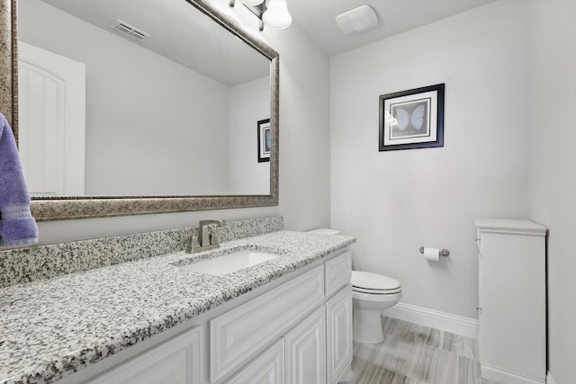 bathroom with visible vents, vanity, toilet, and baseboards