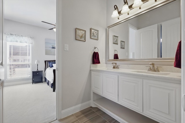 full bathroom with baseboards, double vanity, a sink, and connected bathroom