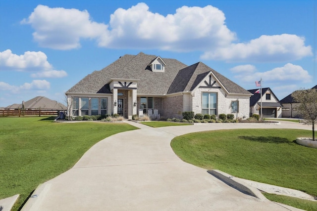 view of front facade with a shingled roof, fence, a front lawn, and concrete driveway