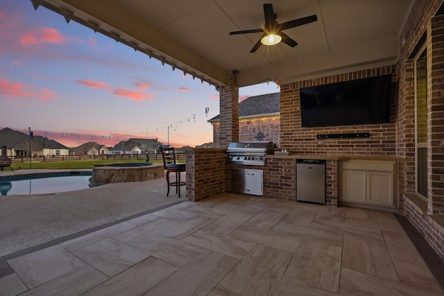 view of patio / terrace with a ceiling fan, area for grilling, fence, exterior kitchen, and a pool with connected hot tub