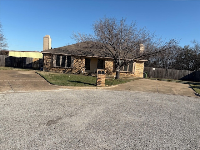 view of front of property featuring a chimney, fence, a front lawn, and brick siding