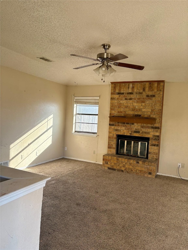 unfurnished living room featuring carpet, ceiling fan, a textured ceiling, and a fireplace