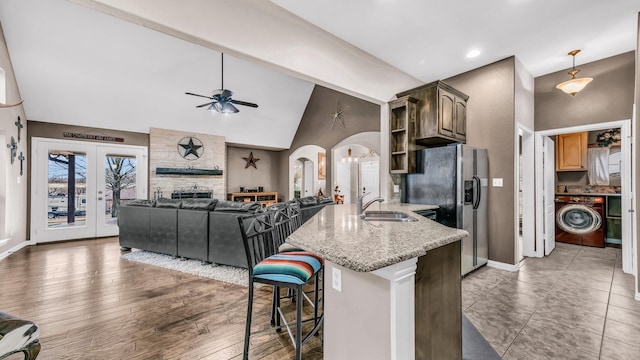 kitchen featuring arched walkways, open shelves, ceiling fan, washer / dryer, and a peninsula