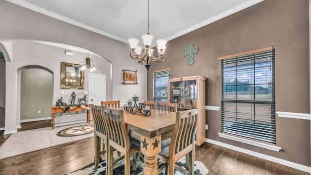 dining space with arched walkways, baseboards, ornamental molding, hardwood / wood-style floors, and an inviting chandelier