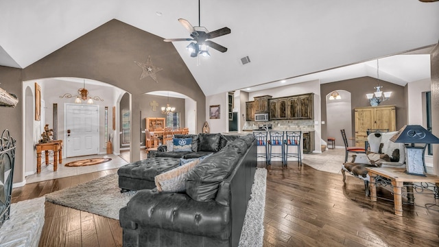 living area with arched walkways, visible vents, high vaulted ceiling, light wood-type flooring, and ceiling fan with notable chandelier