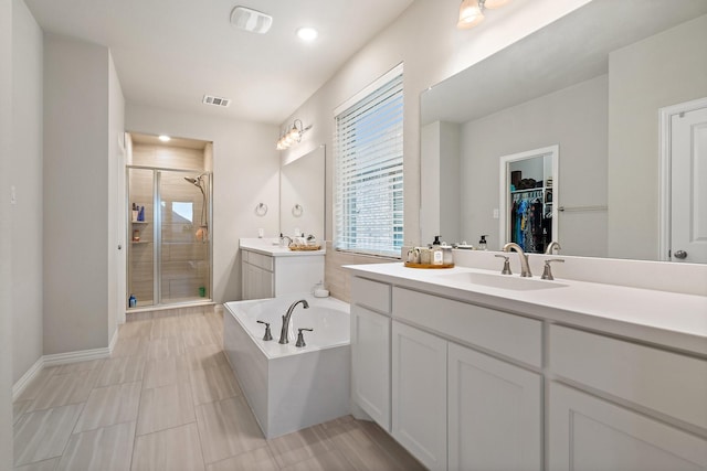 bathroom with a garden tub, two vanities, visible vents, a sink, and a shower stall