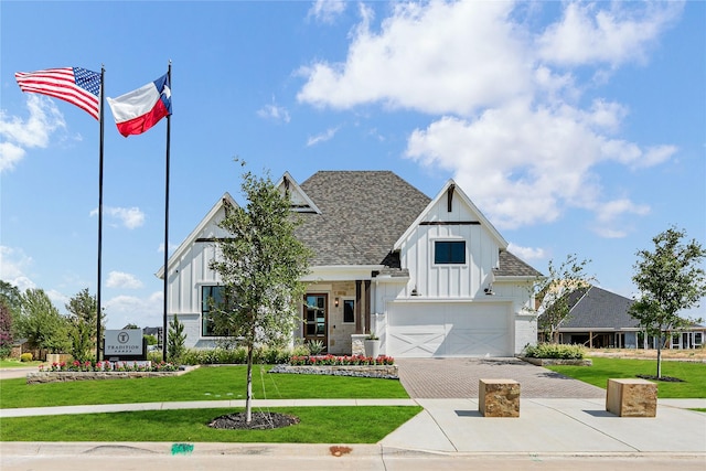 modern farmhouse featuring decorative driveway, roof with shingles, board and batten siding, a front yard, and a garage