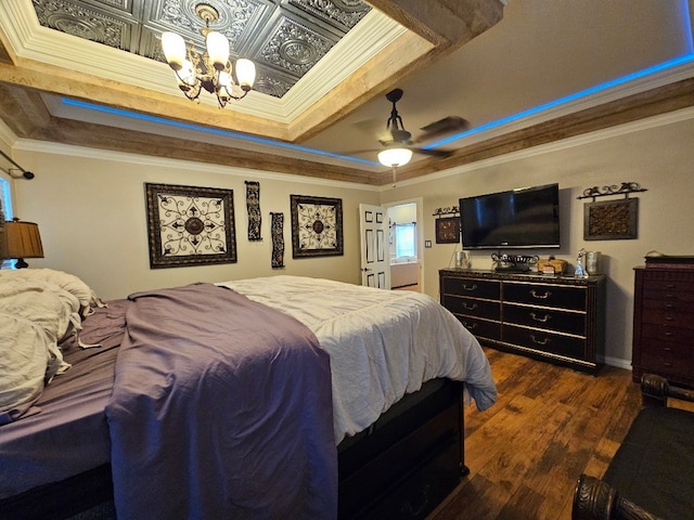 bedroom with ornamental molding, ceiling fan with notable chandelier, dark wood-type flooring, and a tray ceiling