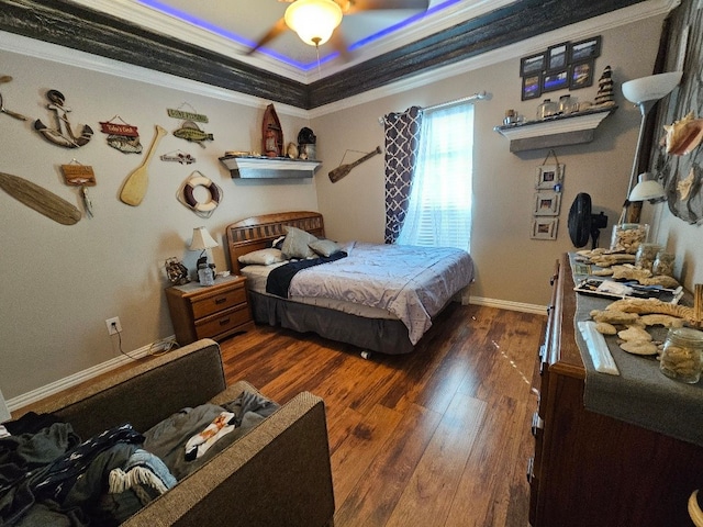 bedroom featuring baseboards, ornamental molding, a raised ceiling, and hardwood / wood-style floors