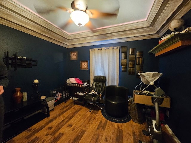 sitting room featuring wood finished floors, ceiling fan, crown molding, and a tray ceiling