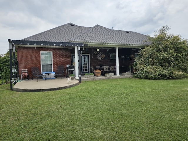 rear view of house featuring brick siding, a yard, a shingled roof, and a patio area
