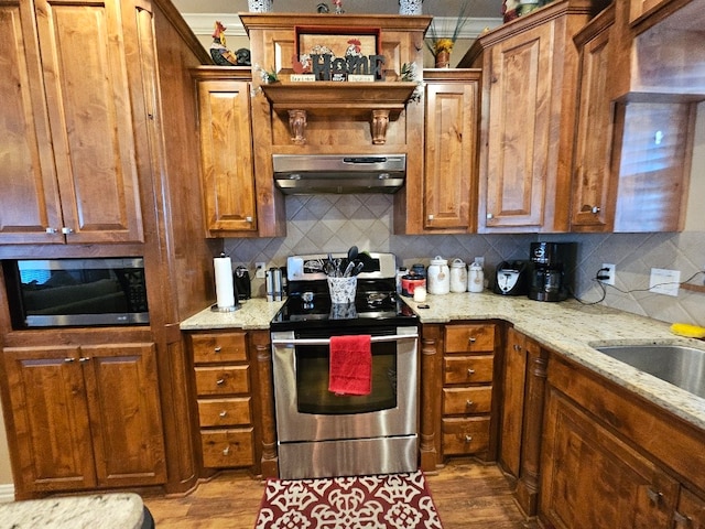 kitchen featuring ventilation hood, tasteful backsplash, stainless steel appliances, and wood finished floors