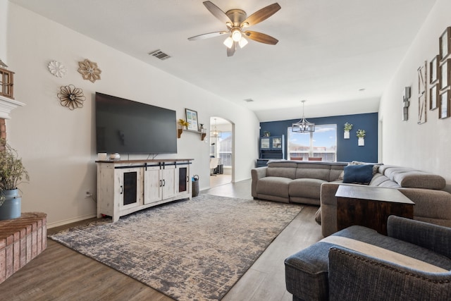 living area featuring visible vents, baseboards, ceiling fan with notable chandelier, wood finished floors, and arched walkways