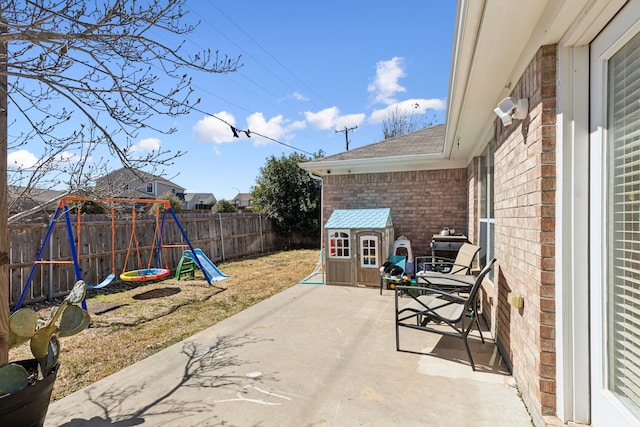 view of patio with a storage shed, a playground, a fenced backyard, and an outdoor structure