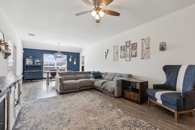 living area featuring visible vents, ceiling fan with notable chandelier, and wood finished floors