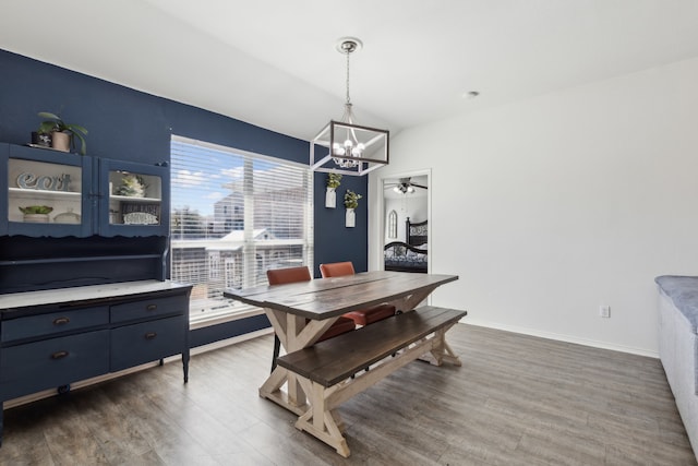 dining area featuring baseboards, dark wood-style flooring, vaulted ceiling, and an inviting chandelier